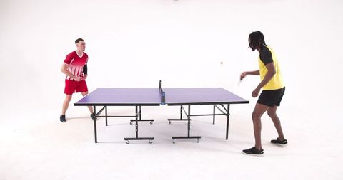 Dual Athletes Engaged in Energetic Indoor Table Tennis Match