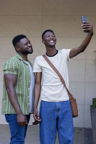 African friends taking selfie outside urban wall sharing joyful moment and smiling
