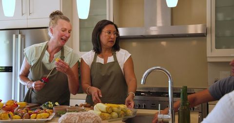 Diverse Women Preparing Colorful Veggie Skewers in Bright Kitchen