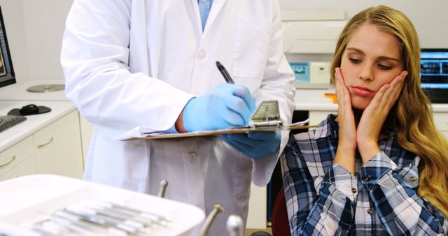 Dentist Consultation with Concerned Female Patient Holding Jaw - Download Free Stock Images Pikwizard.com