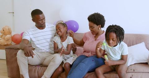 Happy African American Family Playing with Bubbles on Couch