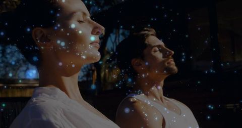 Sunlit Couple Meditating on Deck with Ethereal Blue Particles for Mindfulness and Relaxation