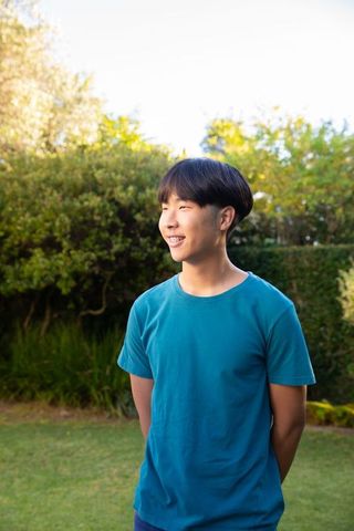 Smiling Young Man in Teal T-shirt on Sunny Day Outdoors