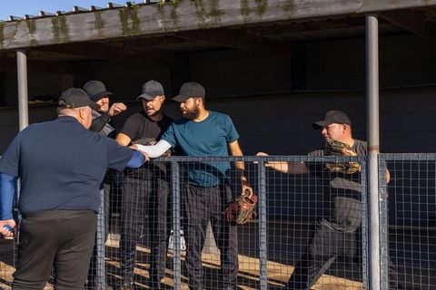 Baseball players fist-bumping coach in sunlit dugout showing teamwork and mentorship