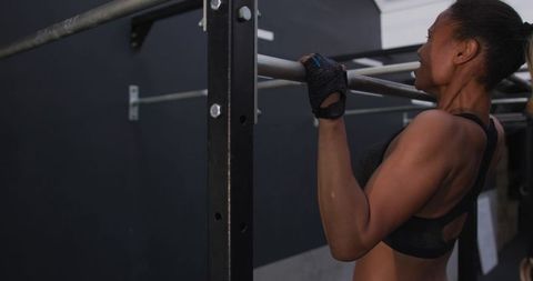 Determined woman practicing pull-ups in urban gym