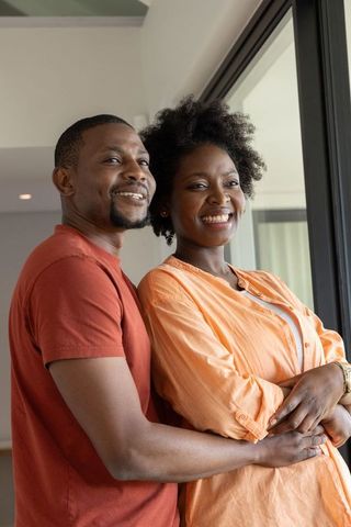 African american couple embracing and smiling in modern condo balcony
