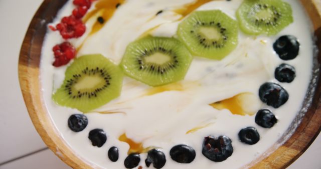 A bowl of yogurt topped with slices of kiwi, blueberries, and a sprinkle of red berries, with copy space. Fresh fruits add a colorful and nutritious touch to this healthy snack option.
