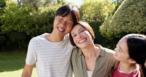 Happy smiling family in lush backyard under sunny sky