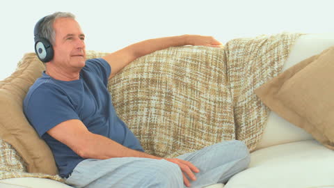 Senior Man Relaxing with Headphones on Couch at Home