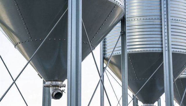 Galvanized conical grain hopper close-up showing discharge flange and steel support