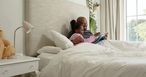 Father and Daughter Relaxing in Cozy Bedroom with Tablet