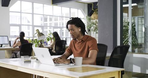 African American Man Working on Laptop in Modern Coworking Office Focused on Productivity