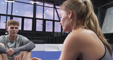 Workout Partners Sitting on Gym Mat Post-Exercise