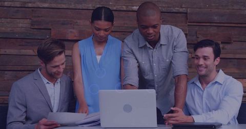 Reviewing business strategy together multiracial team leaning over laptop in rustic office