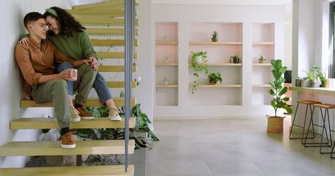 Cozy couple relaxing on modern wooden stairs in minimalist home