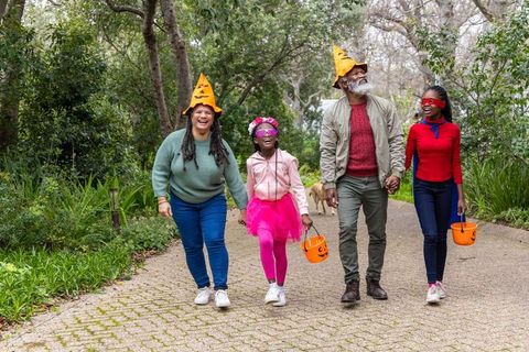 African american multigenerational family walking holding halloween pumpkin buckets