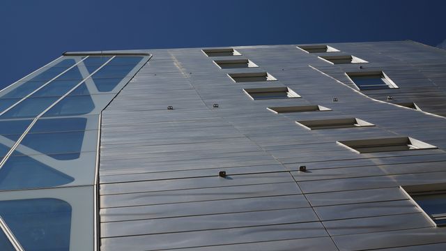 Modern building with metallic facade against clear blue sky - Download Free Stock Images Pikwizard.com