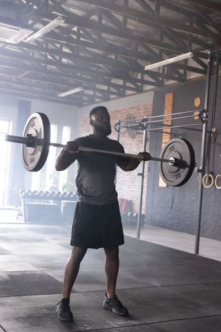 African American Athlete Lifting Heavy Barbell in Industrial Gym, Strength Training in Daylight