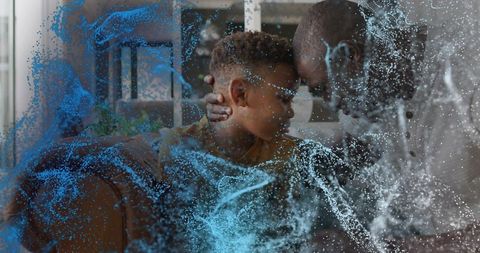 Cradling father and son sharing intimate forehead-to-forehead moment on living room couch