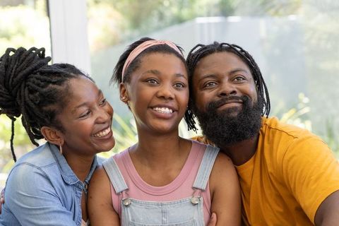 African american family sharing warm moment on sunlit patio, smiling and embracing