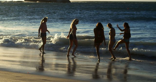 Caucasian women enjoy a playful moment on the beach at sunset. Their laughter and energy capture the essence of carefree summer days by the sea.