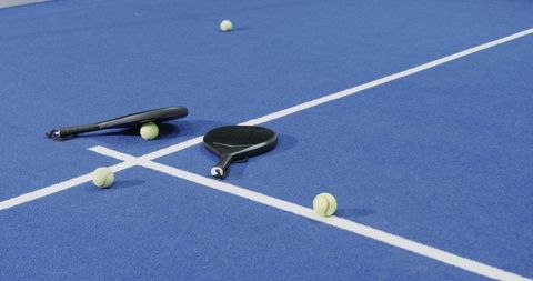 Padel rackets and balls on blue court awaiting action