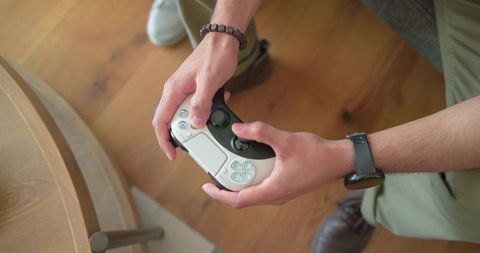 Overhead shot african american mid-adult holding white game controller on hardwood floor