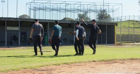 Baseball Teammates Walking Toward Dugout on Sunny Field After Practice