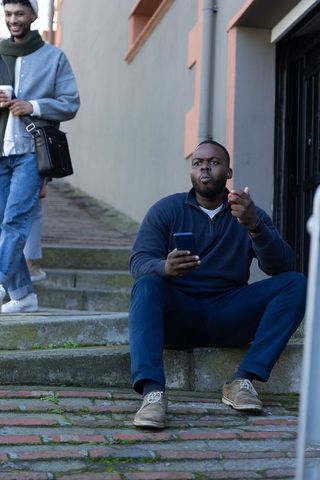 Sitting on brick steps with smartphone and apple, commuter taking urban break