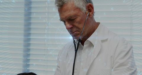 Senior Doctor Performing Stethoscope Examination in Clinic with Venetian Blinds