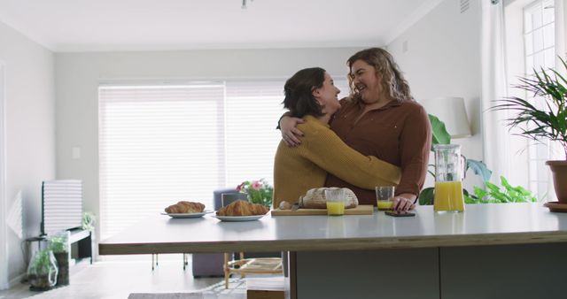 Caucasian lesbian couple embracing and smiling in kitchen. domestic life, spending free time relaxing at home.
