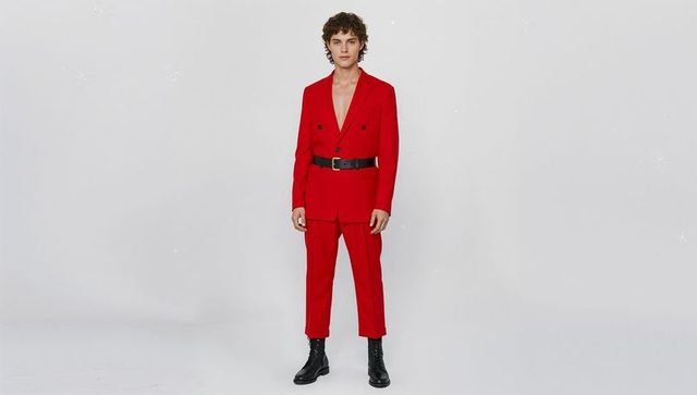 Minimalist male fashion in red suit with black boots: studio setting