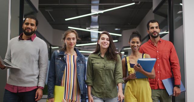 Diverse group of young professionals walking confidently in a modern office hallway. Ideal for use in business, teamwork, corporate environment, diversity and inclusion, and workplace collaboration themes.