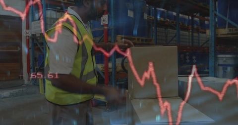 Warehouse packer in high-vis vest packing boxes with overlaid falling graph showing logistics risk