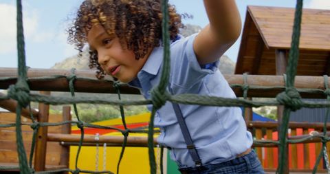 Young Boy with Curly Hair Climbing Rope Structure Outdoors