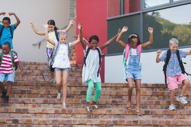 Group of cheerful children descending school stairs with backpacks, expressing joy and excitement. Ideal for educational materials, back-to-school campaigns, and advertisements promoting school supplies or children's activities.