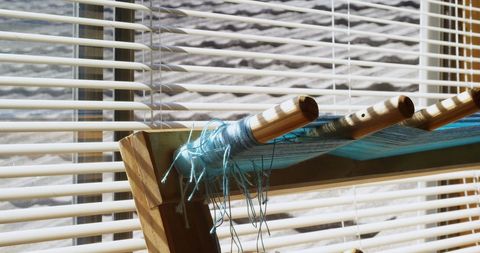 Close-up of threads on inkle loom in sunlit workshop