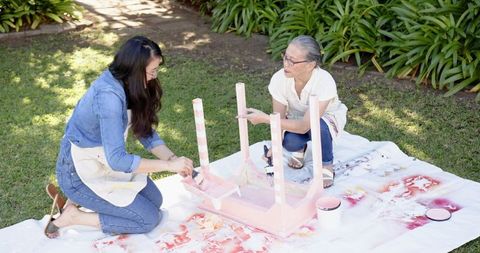 Mother and daughter restoring furniture in garden