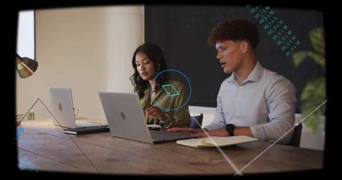 Young professionals collaborating over laptops with digital overlay graphics