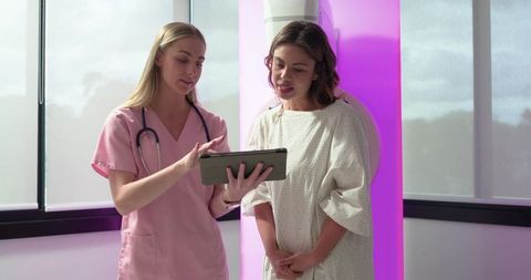 Female clinician explaining scan results on tablet to patient beside purple medical scanner