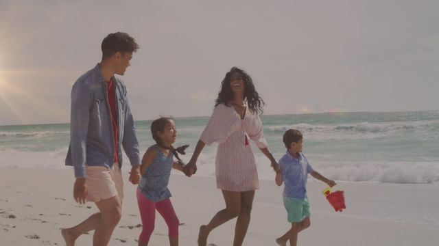 A biracial family, with two adults and two children, are walking happily along a sunny beach with light trails animation surrounding them. Ideal for themes of family bonding, vacations, diversity, and outdoor activities promoting unity and happiness.