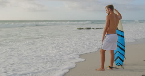 Surfer Gazing at Ocean Waves on Sandy Beach