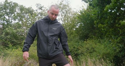 Man exploring green forest in black hiking jacket