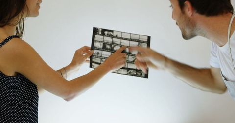 Photographers analyzing film strips in studio with focus