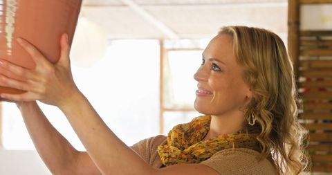 Female potter examining pottery piece in workshop