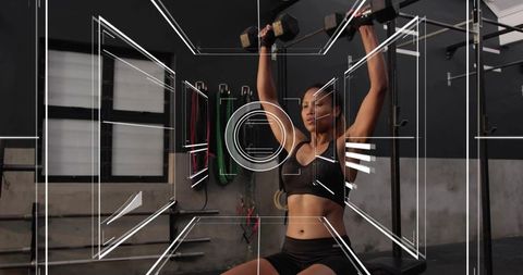 Female Athlete Performing Dumbbell Overhead Press in Industrial Gym with Futuristic HUD
