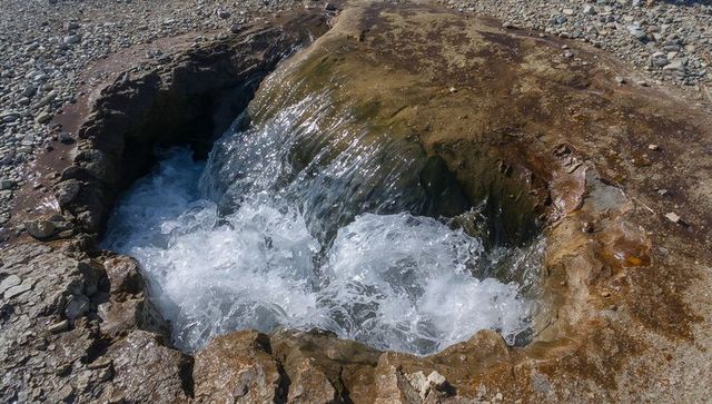 Sea water surging through rocky coastal blowhole creating foaming cascade and tidal pool
