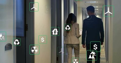Walking coworkers in office corridor with floating sustainability, renewables and finance icons