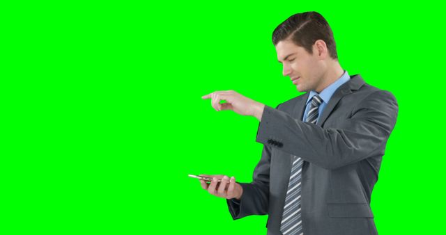 Businessman wearing grey suit and tie using smartphone with green screen background. This can be used for business presentations, marketing materials, web design projects, or technology-related topics.
