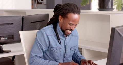 Smiling individual focused on work at office with computers